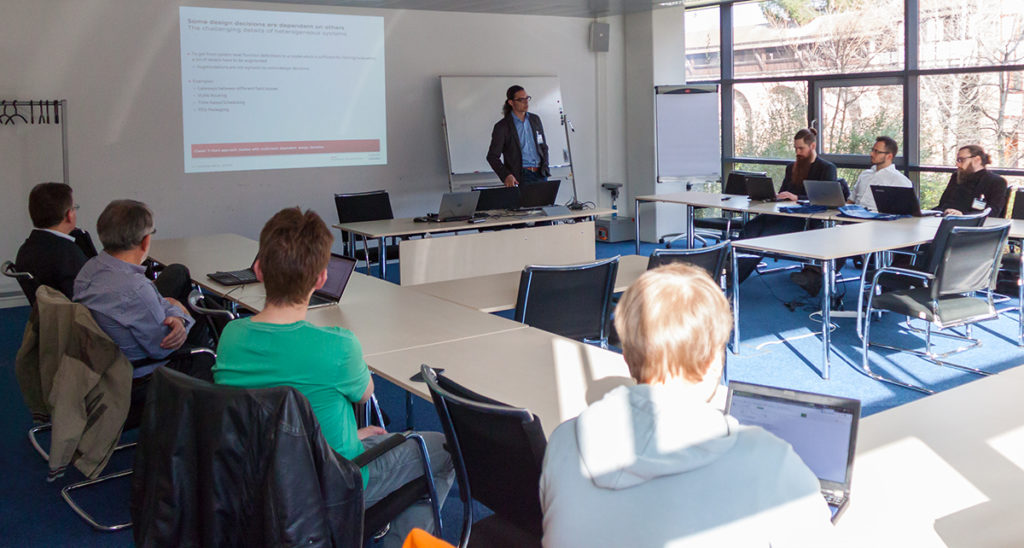 Picture of a seminar room with persons at tables listening to a talking person
