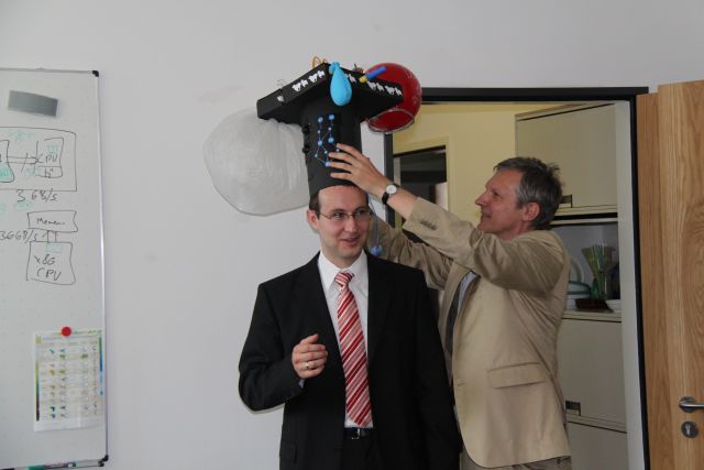 Bild von Sebastian Graf und Prof. Teich, wie er Herrn Graf den Doktorhut aufsetzt