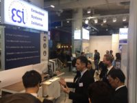 people (i.e. the Thai Delegate) at the booth looking at a presentation of E. Sousa