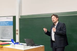 Oliver Keszöcze talking and standing in front of his laptop during his lecture „Entwurf von Mikrofluidischen Biochips“