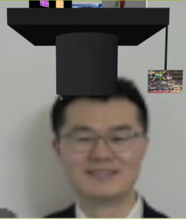 screenshot of head of man with doctoral hat