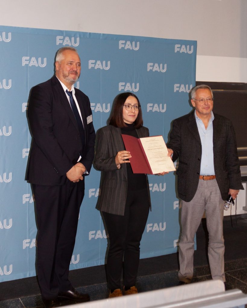 3 persons standing, B. Poumohseni in the middle holding her prize in hands