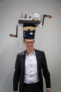 Franz-Josef Streit with his doctoral hat in front of a white wall.