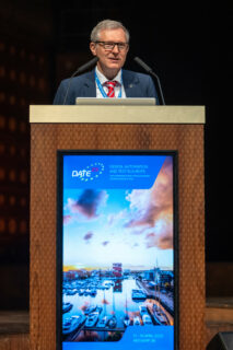 A man speaking behind a desk