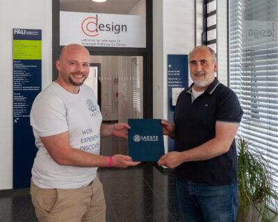 Two persons standing in a hallway holding a certificate