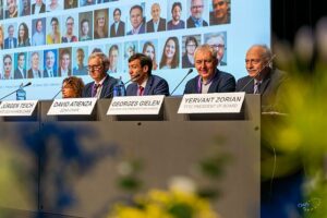 Five persons in a podium sitting before a big screen