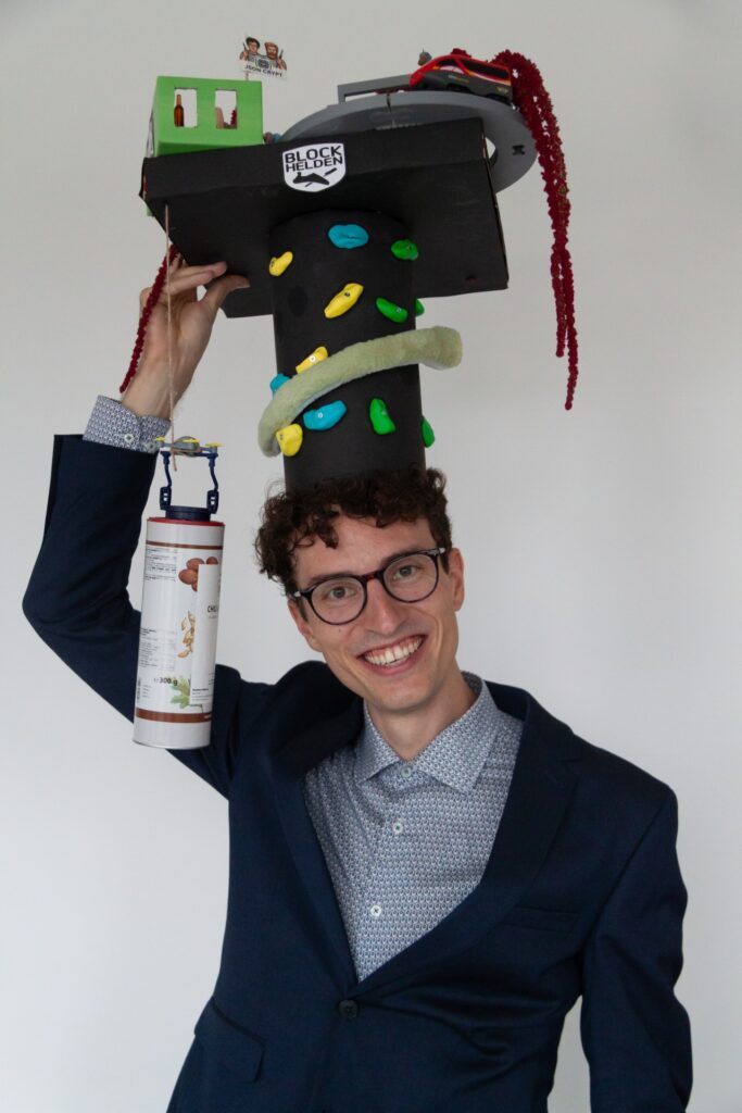 A person in front of a white wall with a doctoral hat